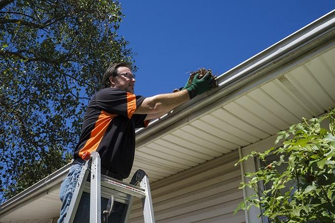 a worker using a ladder to fix a damaged gutter in Alameda